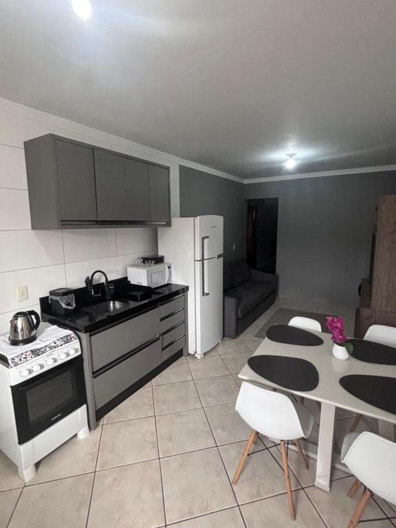 a kitchen with a stove and a refrigerator and a table at Casa em itapema fácil acesso e bem localizada in Itapema