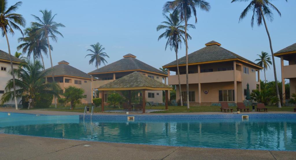 a resort with a swimming pool and palm trees at Elmina Bay Resort in Elmina