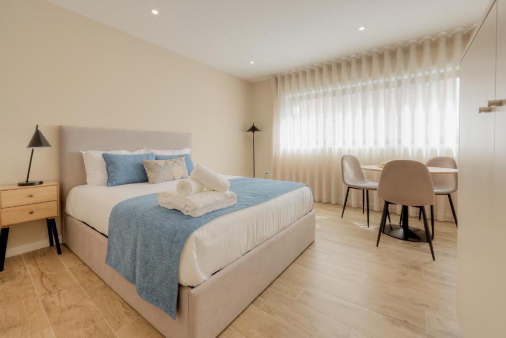 a white bedroom with a bed and a table at Calvário Suites II in Chaves
