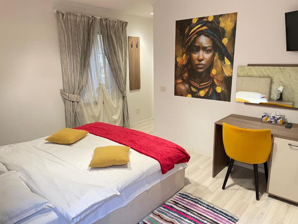 a bedroom with a bed and a desk and a painting at GIADDA Rooms in Borşa