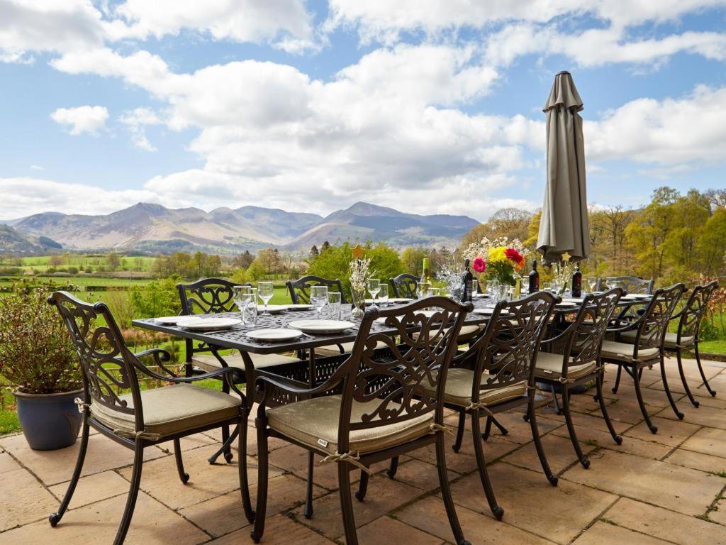 a table with chairs and an umbrella on a patio at 8 Bed in Cumbria oc-sz373 in Applethwaite