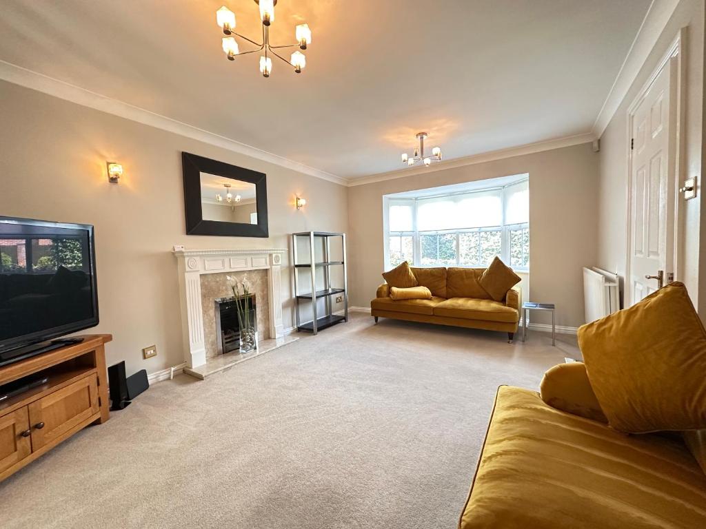 a living room with a couch and a tv and a fireplace at Spacious 4 Bed Home near Elizabeth Line, great for Contractors, Families, Groups & Insurance stays in Romford