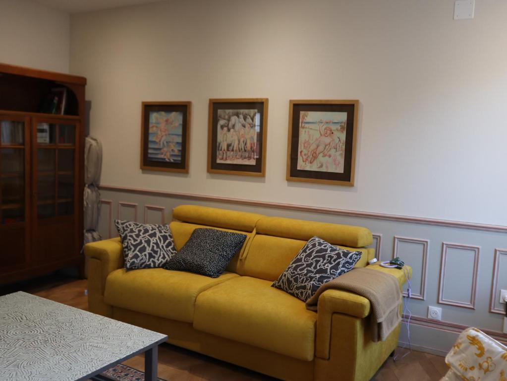 a living room with a yellow couch with pillows on it at Gîte d'artiste in Sainte-Marie-aux-Mines