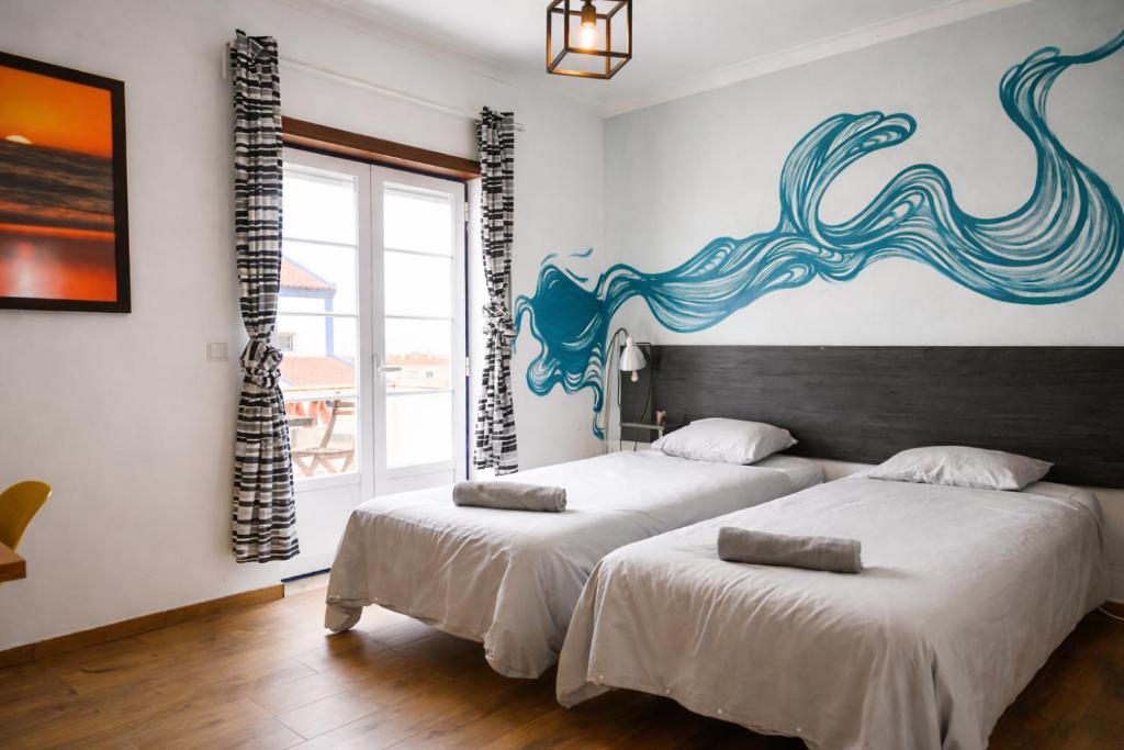 two beds in a room with a painting on the wall at Baleal GuestHouse - Yoga included in Baleal