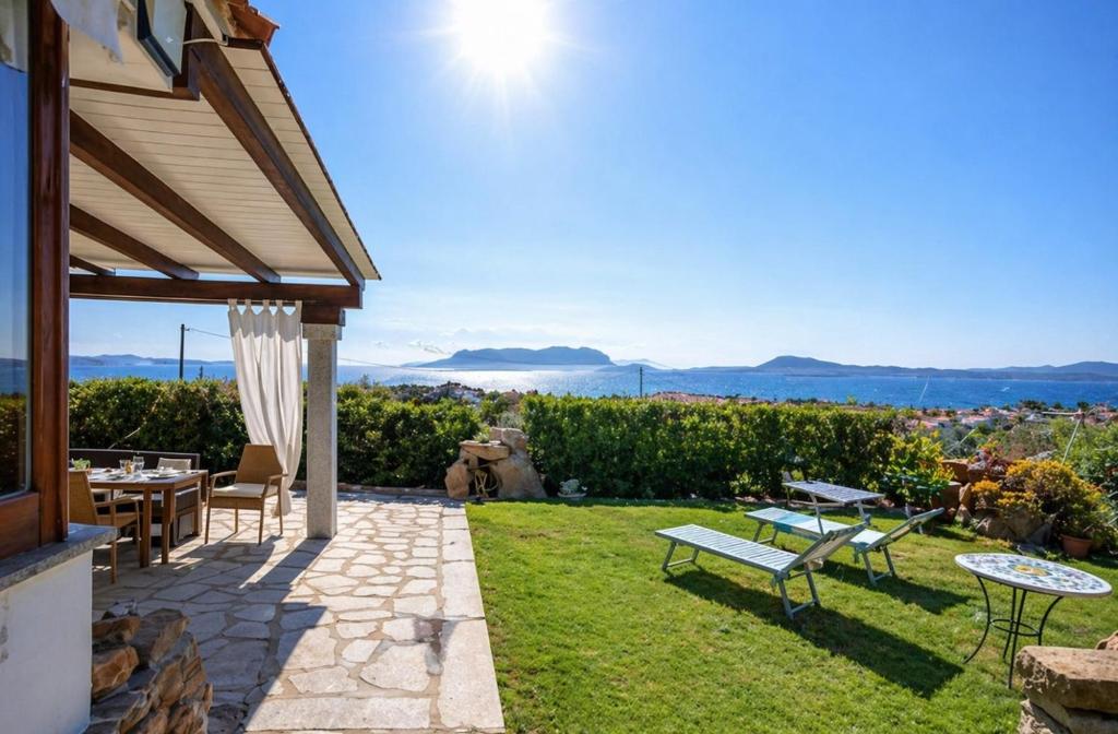 a patio with a table and chairs on a lawn at Bellavista Vacation stunning Tavolara sea view terrace in Olbia