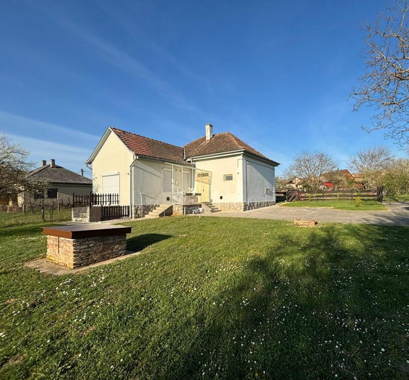 a house with a bench in front of a yard at Holiday house Mernye in Mernye