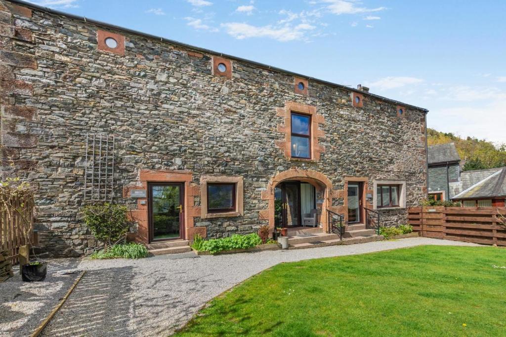 a stone house with a grass yard in front of it at 2 Bed in Keswick oc-28377 in Braithwaite