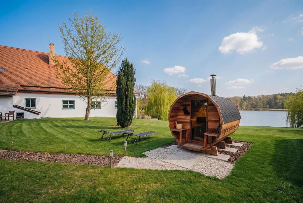 a wooden hobbit house in a yard next to a lake at Bezdrevská Bašta in České Budějovice