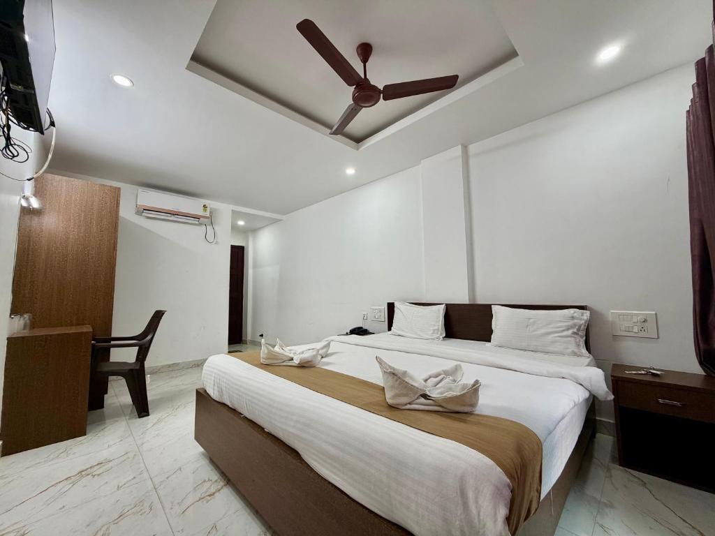 a bedroom with a large bed with a ceiling fan at Hotel Sai in Udupi