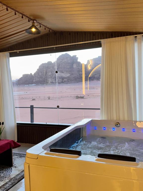 a hot tub in a room with a view of the beach at Wadi Rum Lana luxury camp in Wadi Rum
