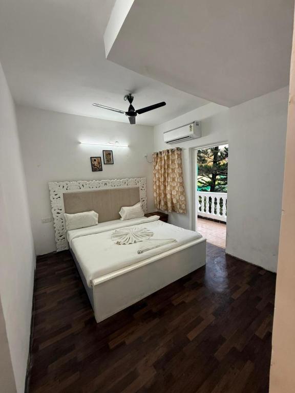 a bedroom with a white bed and a window at Sunshine Park By RoomzAway in Candolim