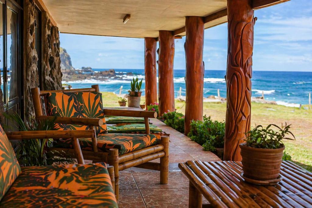 a porch with chairs and a table and the ocean at Cabañas & Hostal Tojika in Hanga Roa