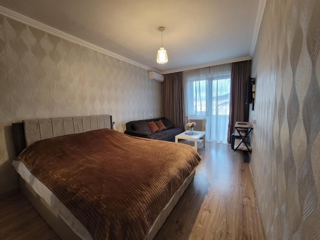 a bedroom with a large bed and a couch at Elan apartment in Gori