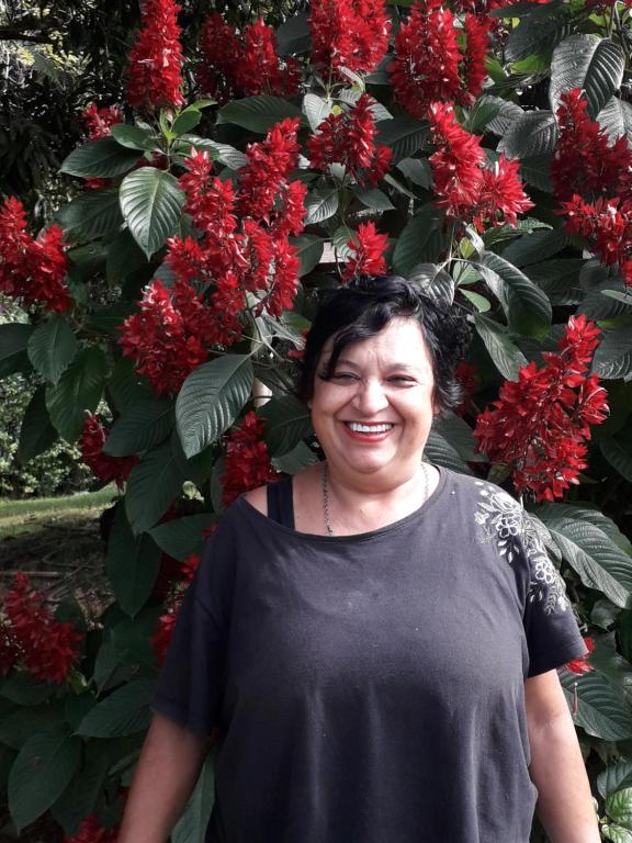 a woman standing in front of a bush with red flowers at Bella Serra in Iporanga