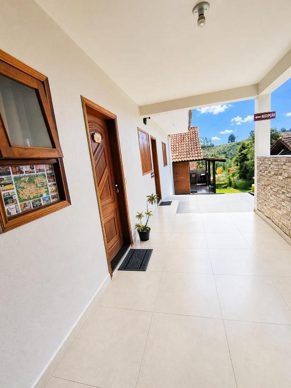 an empty hallway with a door and a tile floor at Chalés e suítes lima in Monte Verde
