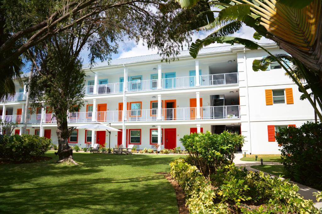 a large white building with orange doors and trees at The Sunshine Hotel and Suites in George Town