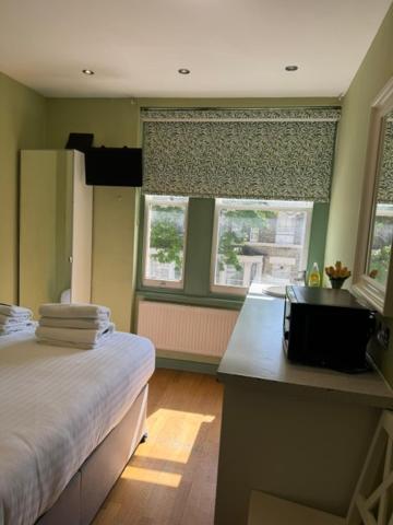 a bedroom with a bed and a desk and two windows at Matheson Olympia Hotel in London