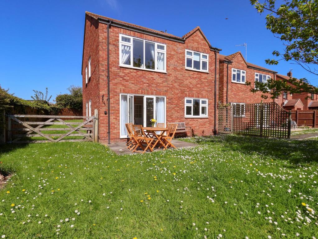 a brick house with a picnic table in the yard at Seashells at Runswick Lodge in Saltburn-by-the-Sea