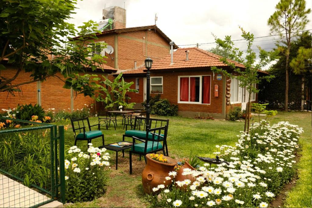 a yard with chairs and flowers in front of a house at Cabañas Yunyay in Villa Cura Brochero
