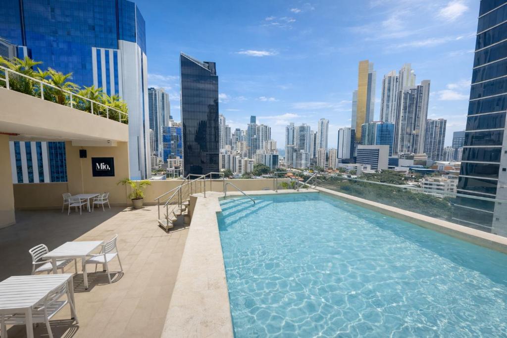 a swimming pool on the roof of a building with a city skyline at Hotel Mio Panamá in Panama City