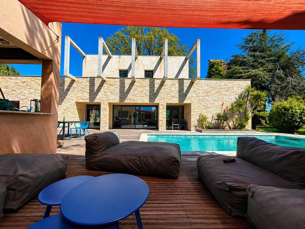 a patio with a couch and tables and a pool at Maison ROMIA in Fréjus