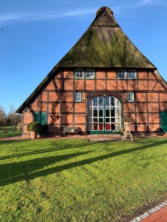 a large building with a thatched roof on a grass field at Reet-Denkmal am Elbstrand in Stade