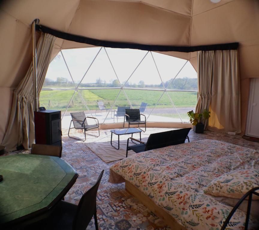 a bedroom with a bed and a table and chairs at Nuit Insolite dôme Reinette tout confort in Châtenois