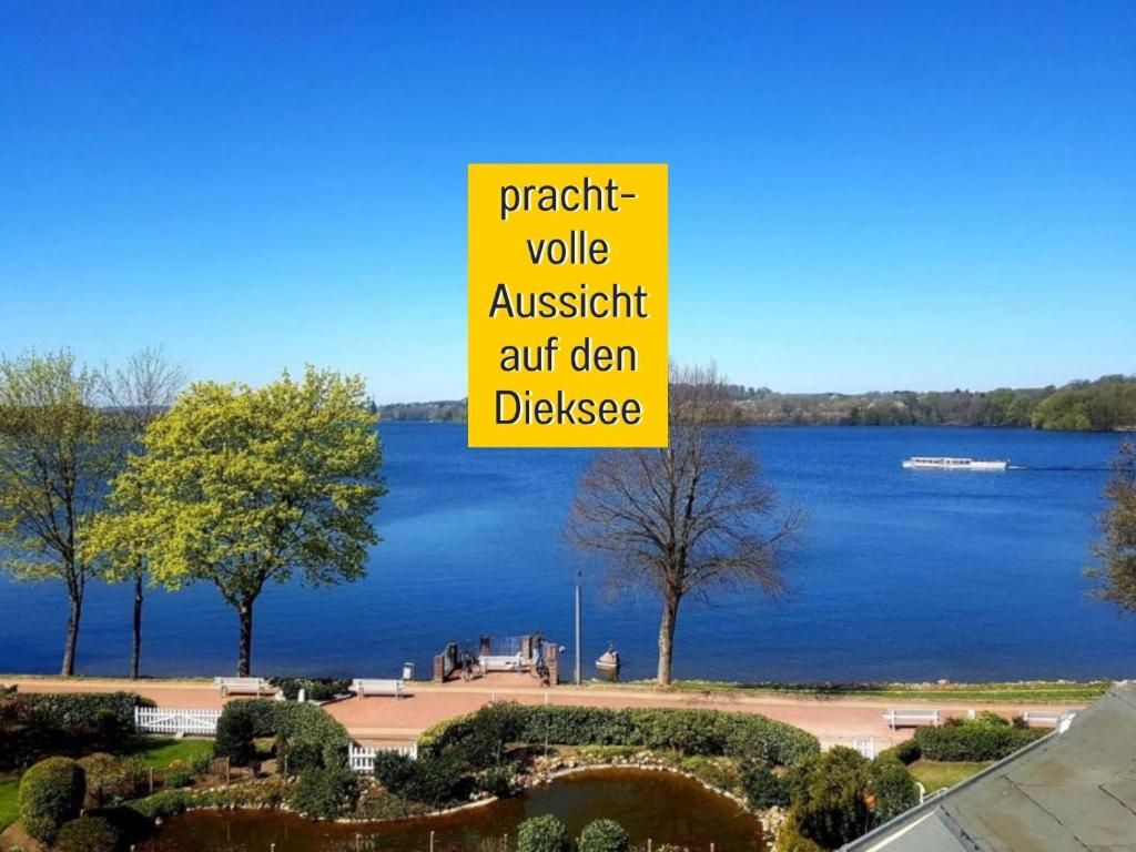 a view of a lake with a sign that reads predict value austbush antdn at Heimathafen Dieksee - mit direktem Seeblick & Balkon am Dieksee in Malente