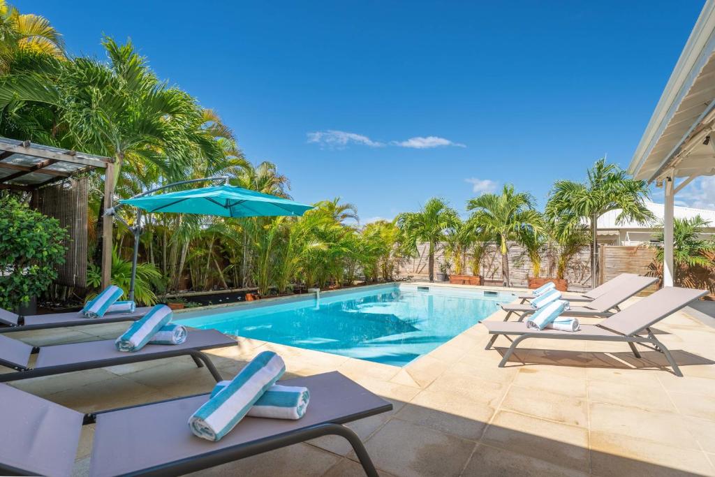 a swimming pool with lounge chairs and an umbrella at Villa Ti'Palm in Saint-François