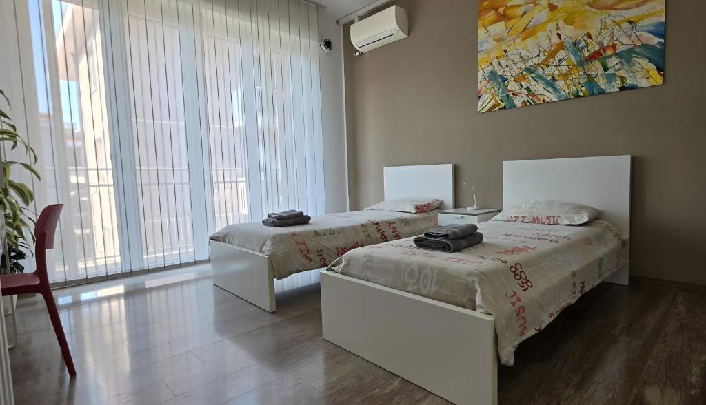 a bedroom with two beds and a large window at CMBYN Stanza in Casa Condivisa e Bici Gratis in Crema