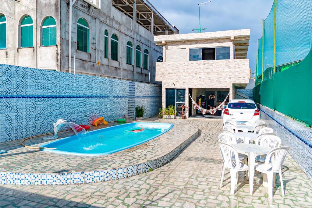 a swimming pool with a table and chairs and a car at Casa Espaço Gaibu in Cabo de Santo Agostinho