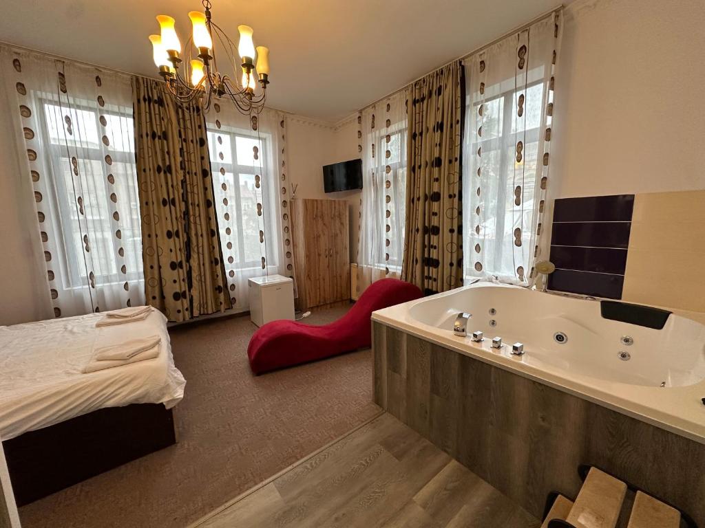 a bathroom with a tub and a bed in a room at LuxInn in Bucharest