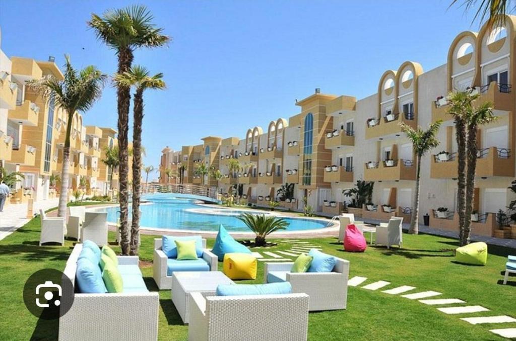 a resort with a pool and chairs and palm trees at Coin de Mire in Hammam Sousse