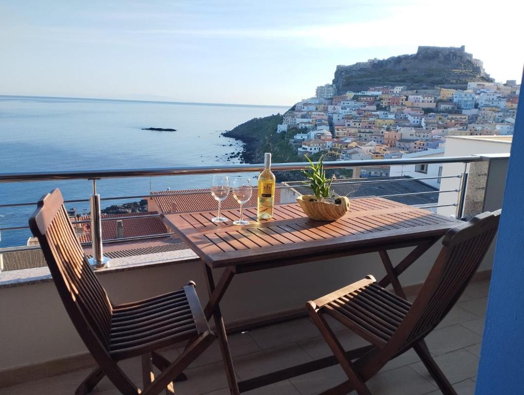 a table with a bottle of wine and glasses on a balcony at Cara a' mari in Castelsardo