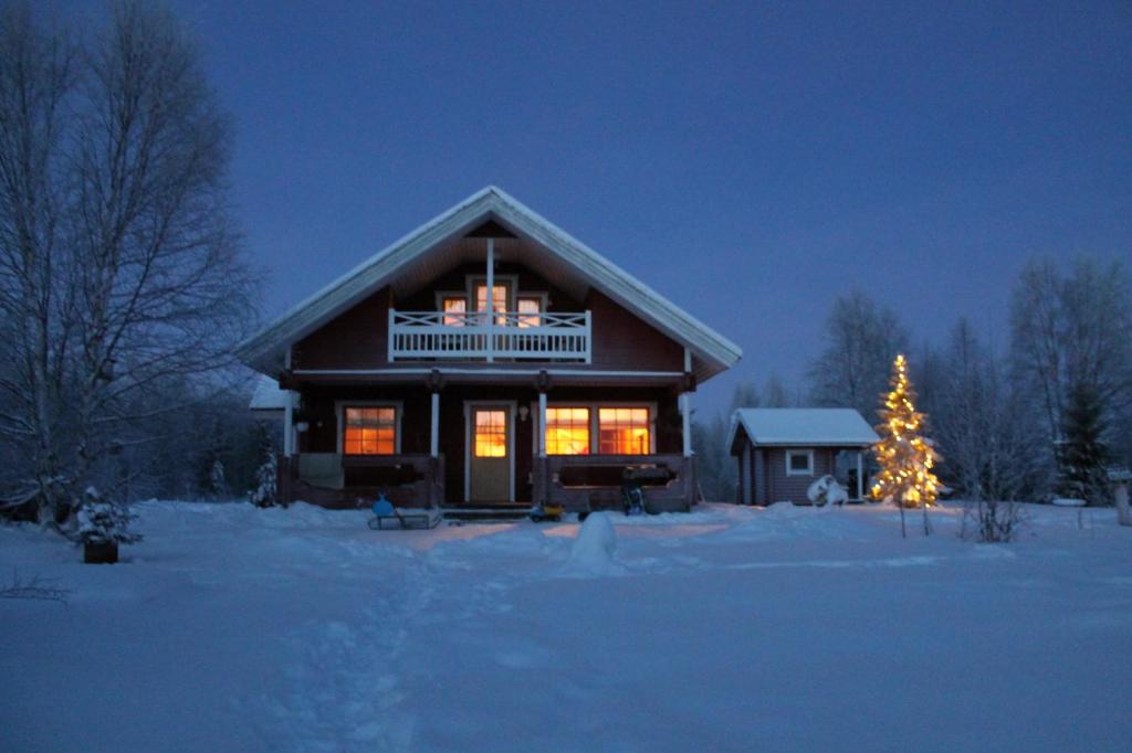 a house with a christmas tree in the snow at Lovely Cottage by Ounasjoki in Marraskoski