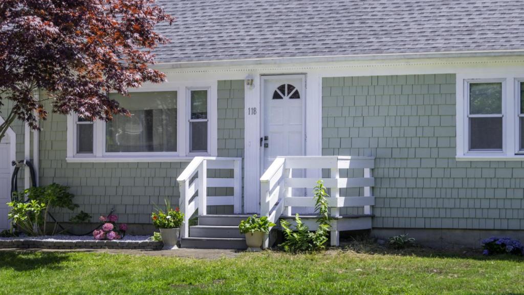a green house with a white door and a porch at Centrally Located, Outdoor Dinning and Game Table in Barnstable