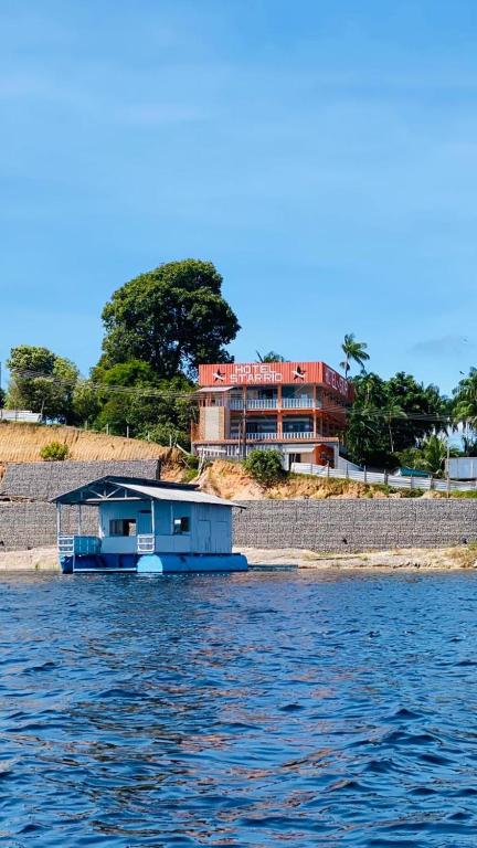 a boat on the water in front of a house at Hotel Star Rio in Novo Airão