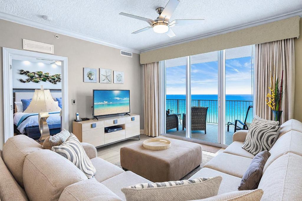a living room with a couch and a tv and a bedroom at Luxury Beachfront Condo Free Beach Chairs Huge Balcony Come Relax! in Panama City Beach