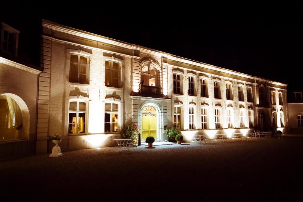 a lit up building with a yellow door at night at Château De Cocove in Recques-sur-Hem
