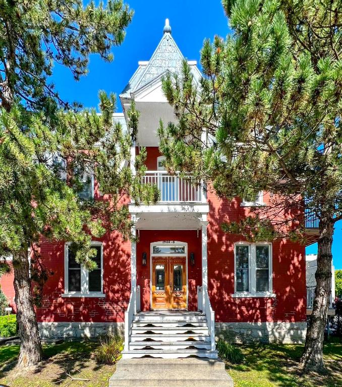 a red house with trees in front of it at Maison Jodoin - Suite Albert in Saint-Hyacinthe