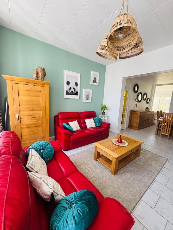 a living room with a red couch and a table at La Maison du Chenal in Gravelines