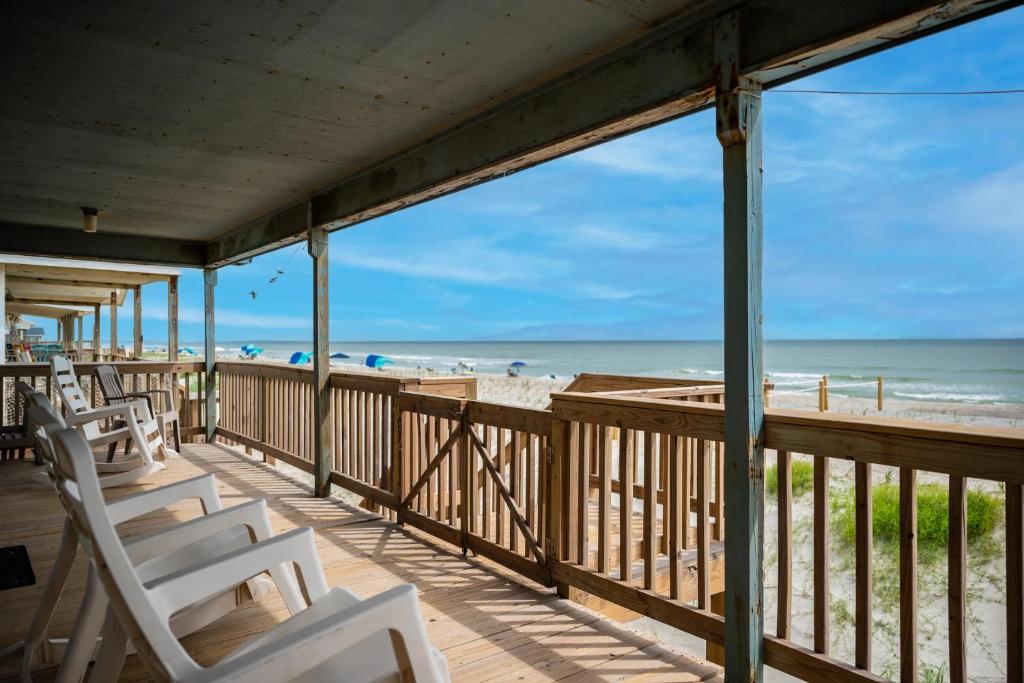 a porch with white chairs and the beach at Blue Haven by Oak Island Accommodations in Oak Island