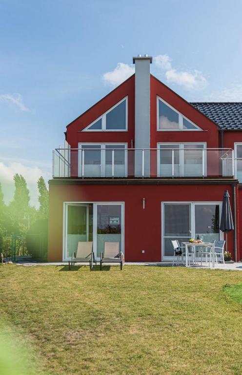 a red house with a table and chairs in a yard at FeWo Sanfte Brise im EG mit Blick in die Natur in Göhren-Lebbin