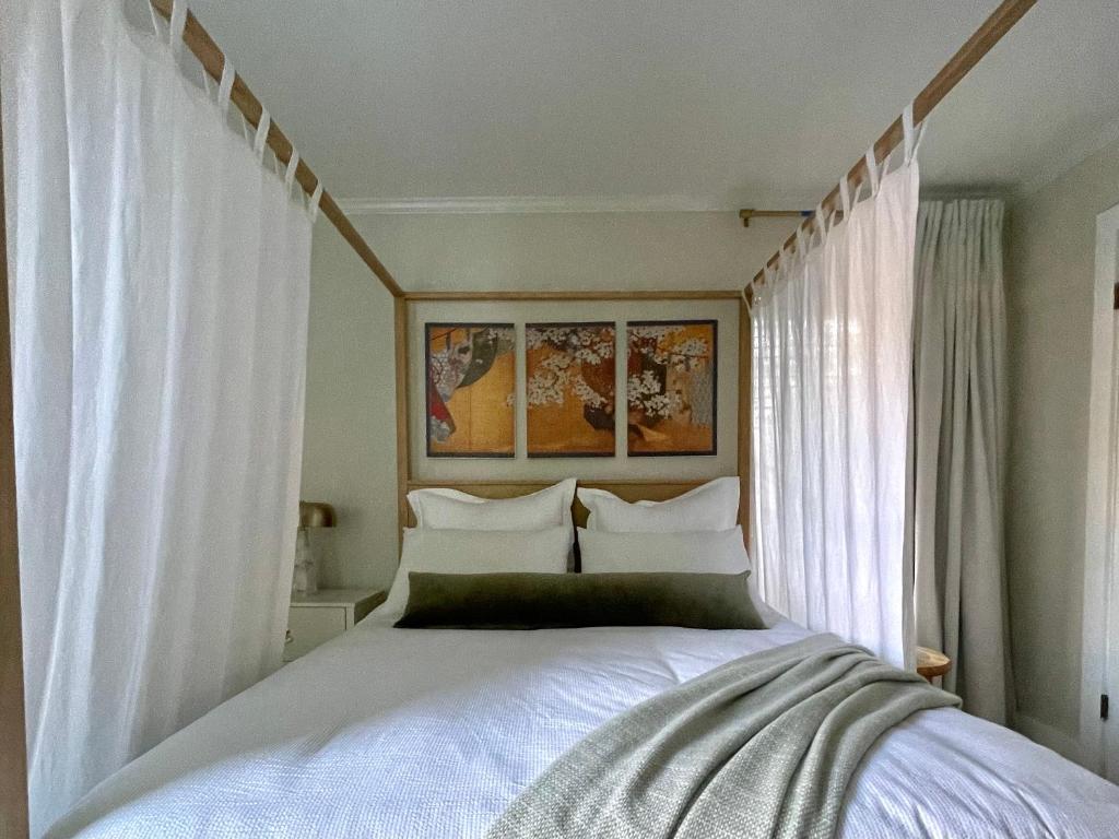 a bedroom with a bed with white sheets and curtains at The Tamara Suite in Pensacola