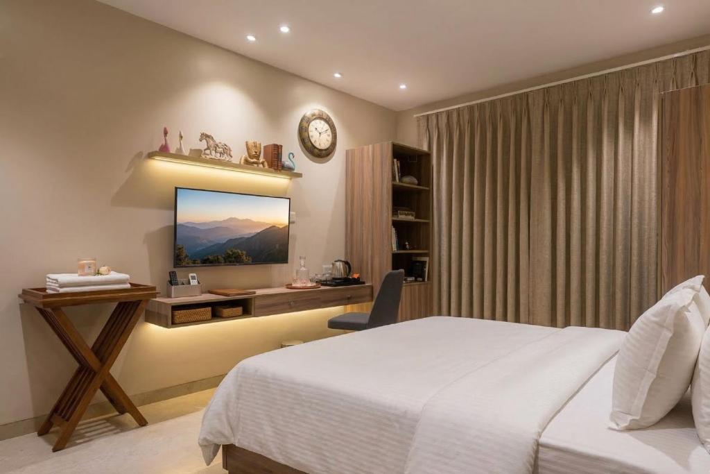 a bedroom with a bed and a desk and a television at Swaranjali in Chikhli