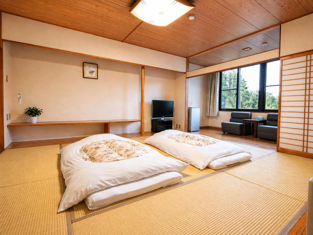 two beds in a room with a living room at Resort Project Myoko Kogen Hot Spring in Myoko