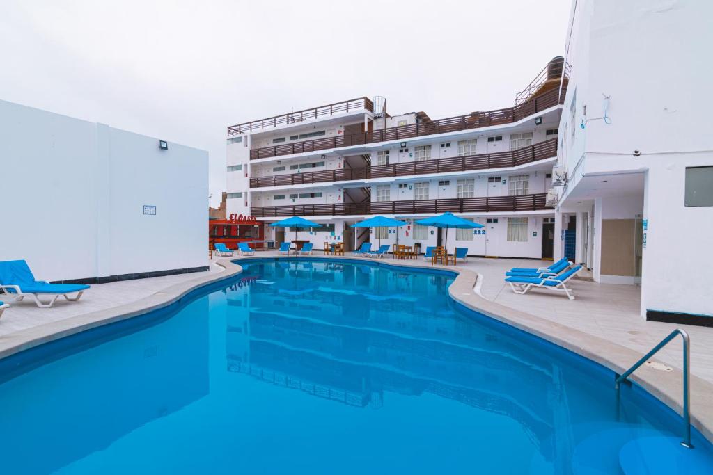 a pool with chairs and umbrellas in front of a hotel at Hotel el Silencio in Bombiso