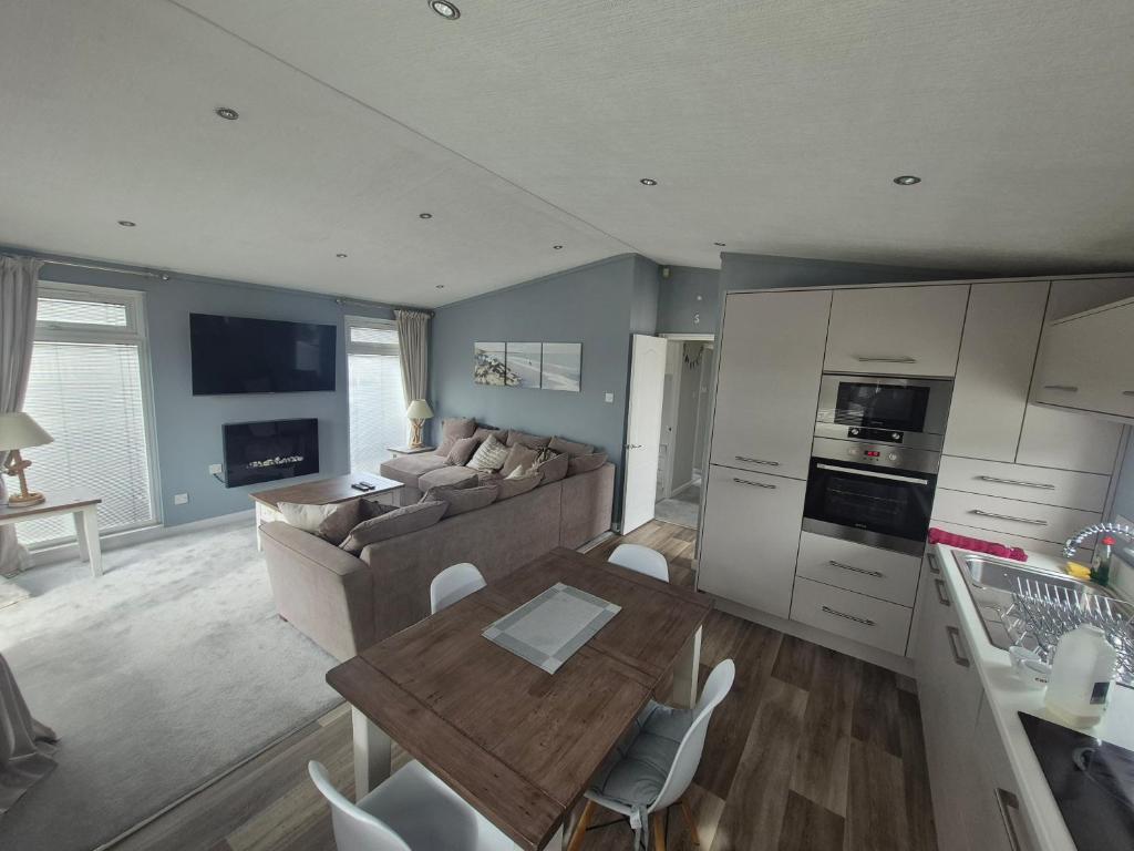 a kitchen and living room with a table and a couch at P1 The Warren Abersoch in Llanbedrog