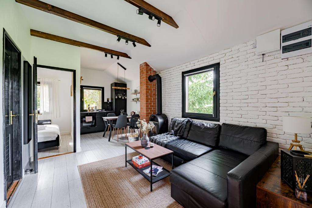 a living room with a black couch and a brick wall at Bodony Cottage in Bodony