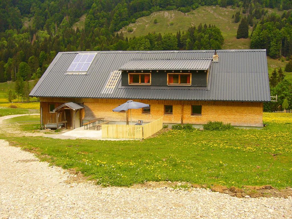 ein Haus mit einem Sonnendach auf einem Grasfeld in der Unterkunft Ferienhütte Kälberweide in Hittisau